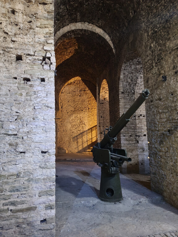 A mechanical gun from a tank, nestled in the columns of Gjirokastra Castle