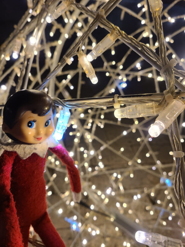 An elf on the shelf poses with Christmas lights in Dubrovnik