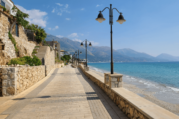 The promenade at lower Qeparo above the blue water of the ocean and the sandy beach