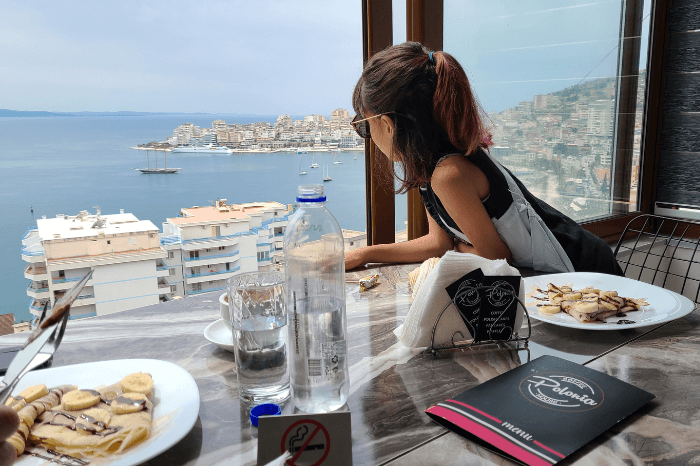 A girl looks out a window far above the bay of Saranda