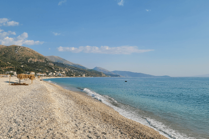 The pebbly beach of Borsh with bright colored waters and hills in the background