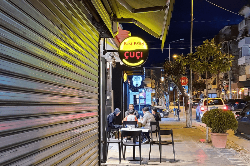 Fast food Cuci sign lit up on the street in Saranda at night. The best place for gyros in Saranda.