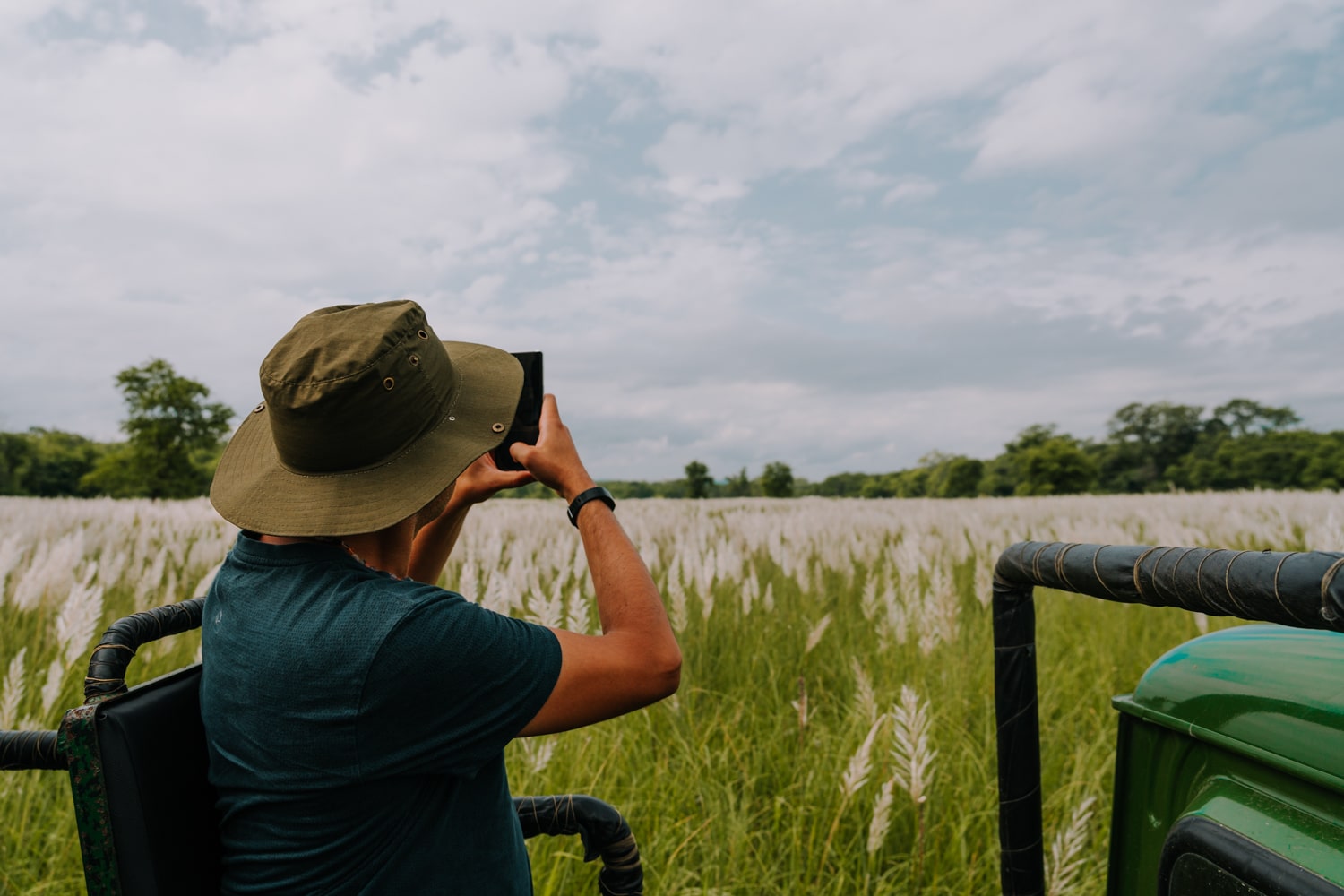 A male tourist takes a photo on jeep safari in Chitwan National Park, Nepal.