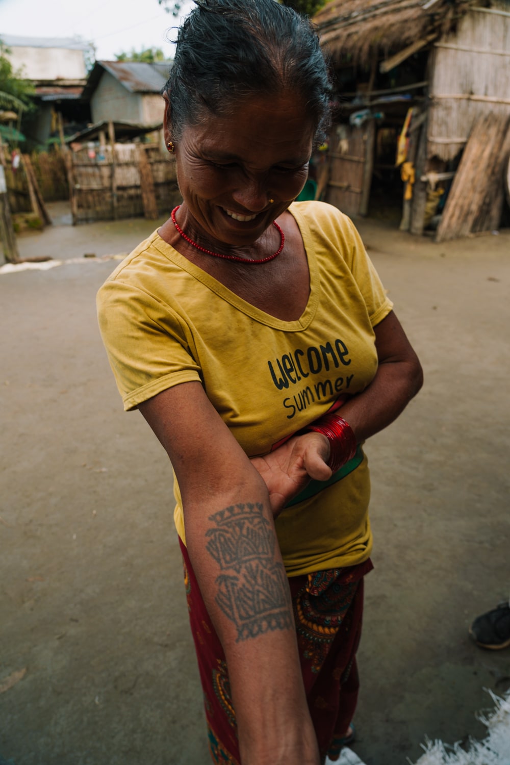 A Tharu woman smiles and shows her arm tattoo in Barauli village.