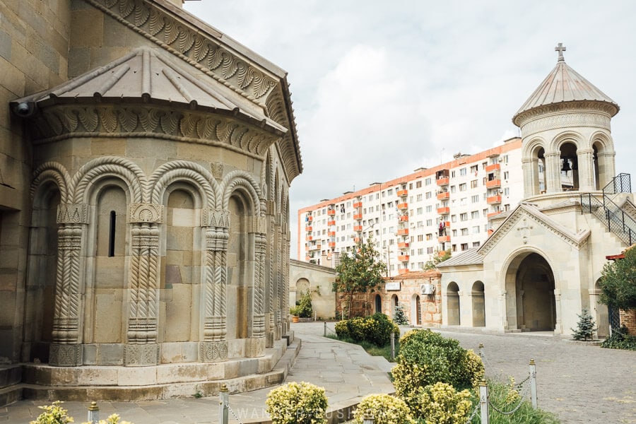 Rustavi Sioni, a beautiful stone church with carvings and a backdrop of apartment buildings.