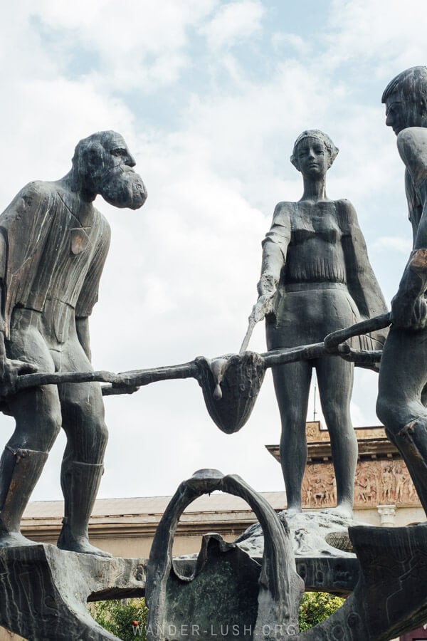 A sculpture depicts three people smelting metal in front of the Rustavi Metallurgy Plant.