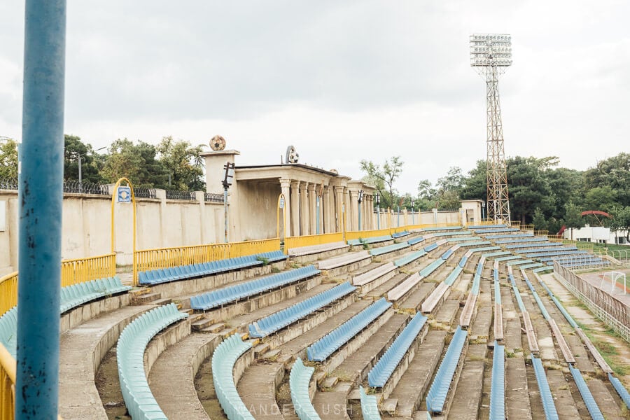 Colourful bleachers inside Rustavi Stadium with a big light overhead.