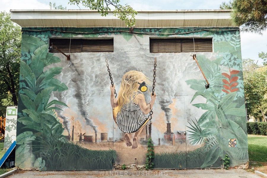 A street art mural in Rustavi on the side of a building depicts a young girl in a gas mask.