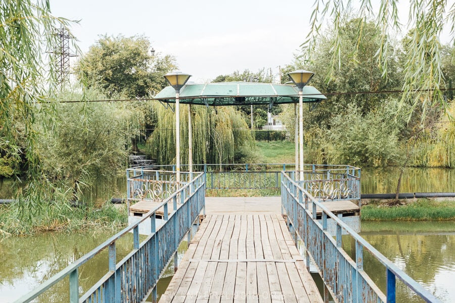 A pier over the lake surrounded by greenery and weeping willows in Rustavi, Georgia.