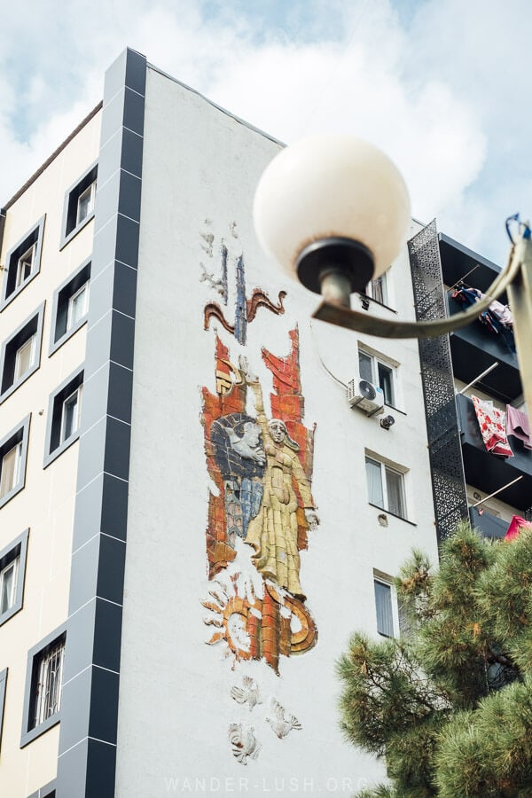 A Soviet era artwork on the front of an apartment block in Rustavi, Georgia depicting a woman reaching her arm overhead.