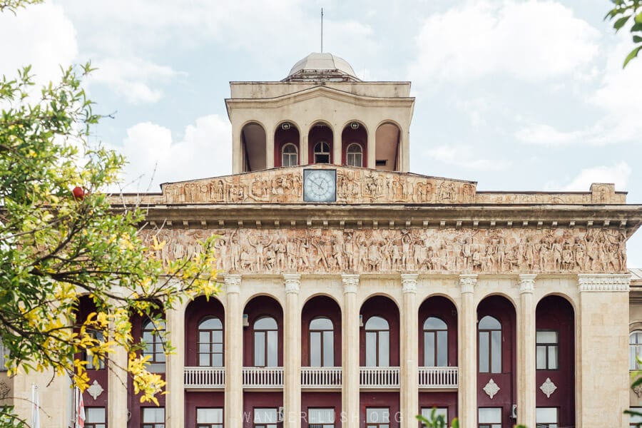 Facade of the Soviet-built Rustavi Metallurgy Plant, a grand building with arches, columns, and bas-relief sculptures along the front.