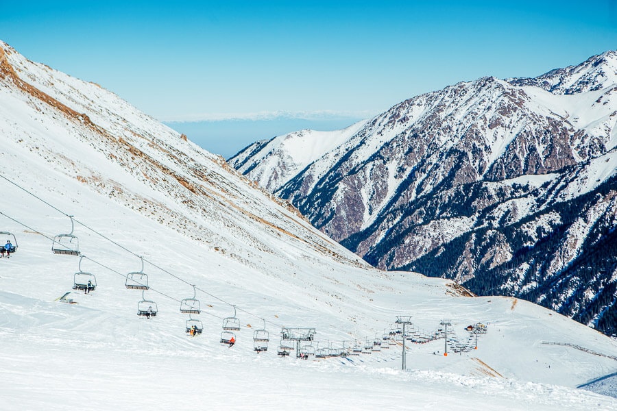 A long chairlift carries people across a mountain landscape in the alternative skiing destination of Shymbulak, Kazakhstan.