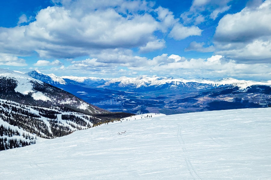 Ski trail stretch into the distance towards blue mountains in the Marmot Basin ski resort.