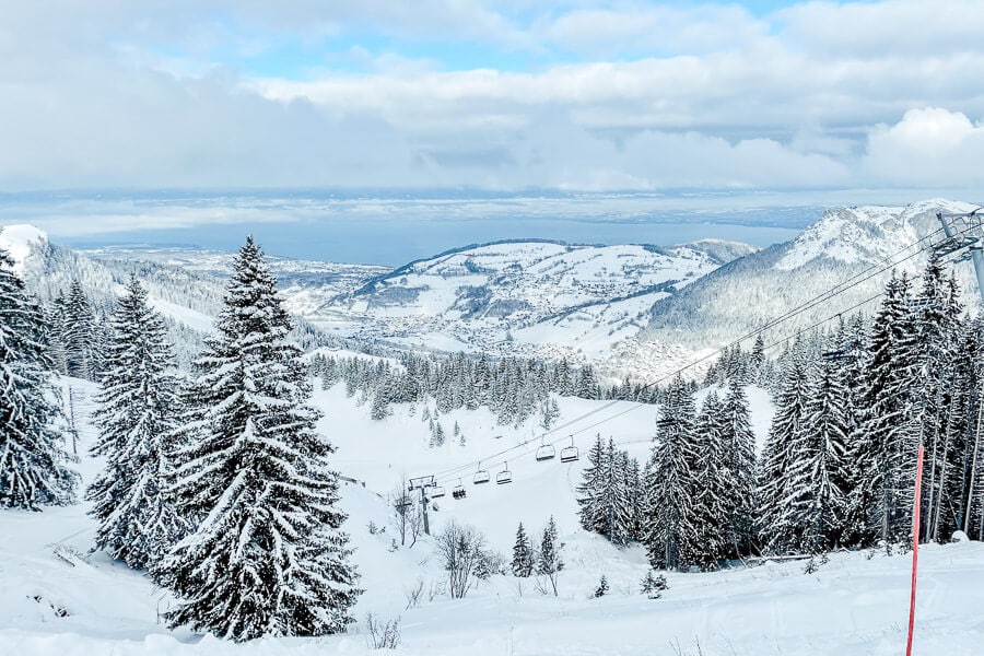 A cable car running through the trees at the Bernex Ski Resort in France under a thick blanket of snow.