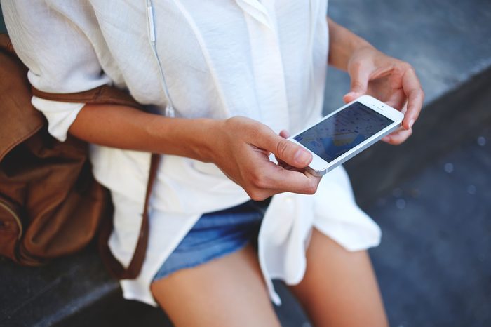 Cropped shot view of woman tourist holding mobile smart phone with navigation application and planned route on the screen, female looking at something on a cell telephone while touring a foreign city