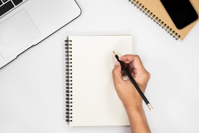 human hand holding pencil prepare to writing on blank notebook.