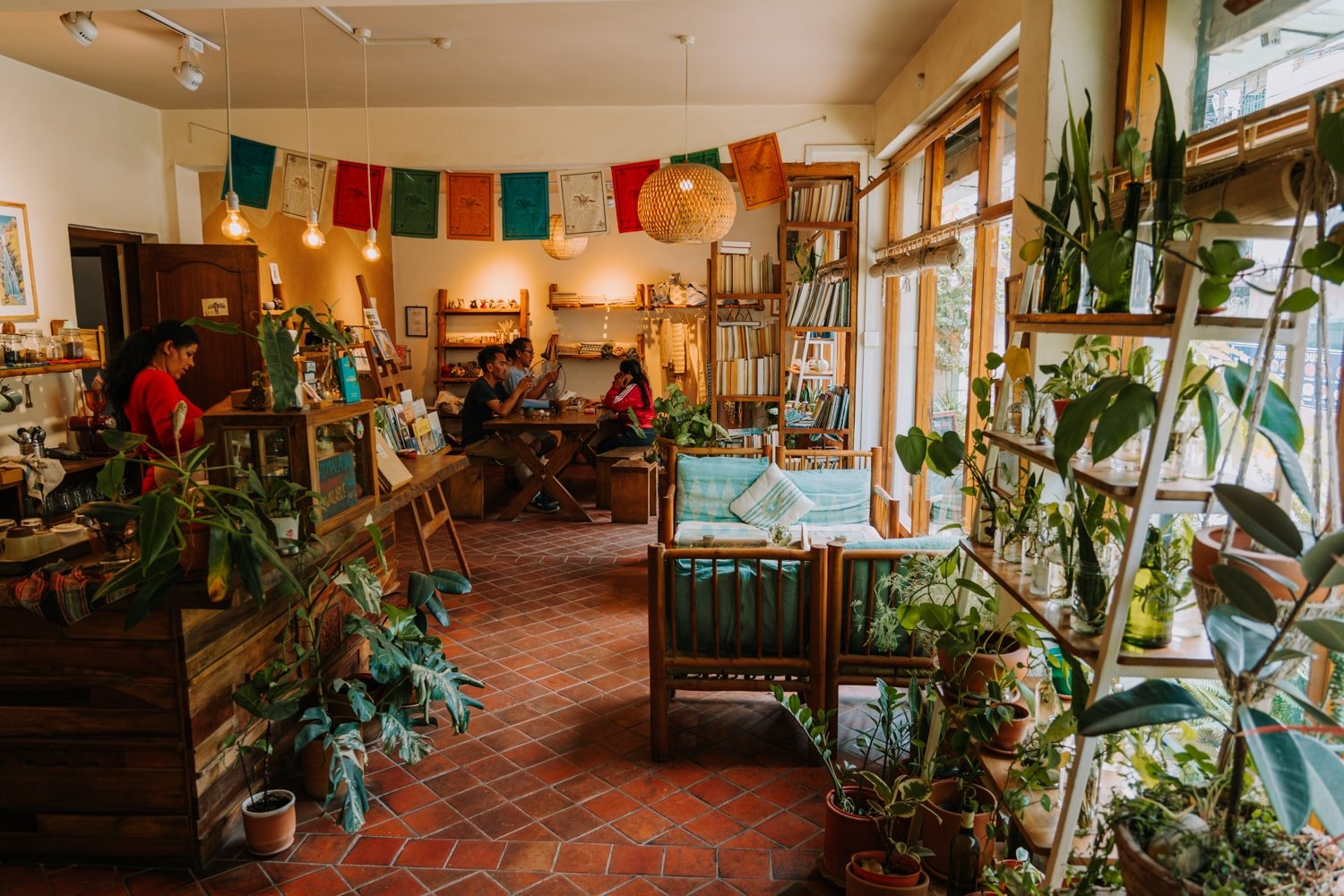 A plant and book-filled cafe in Kathmandu with earthy tones and prayer flags.