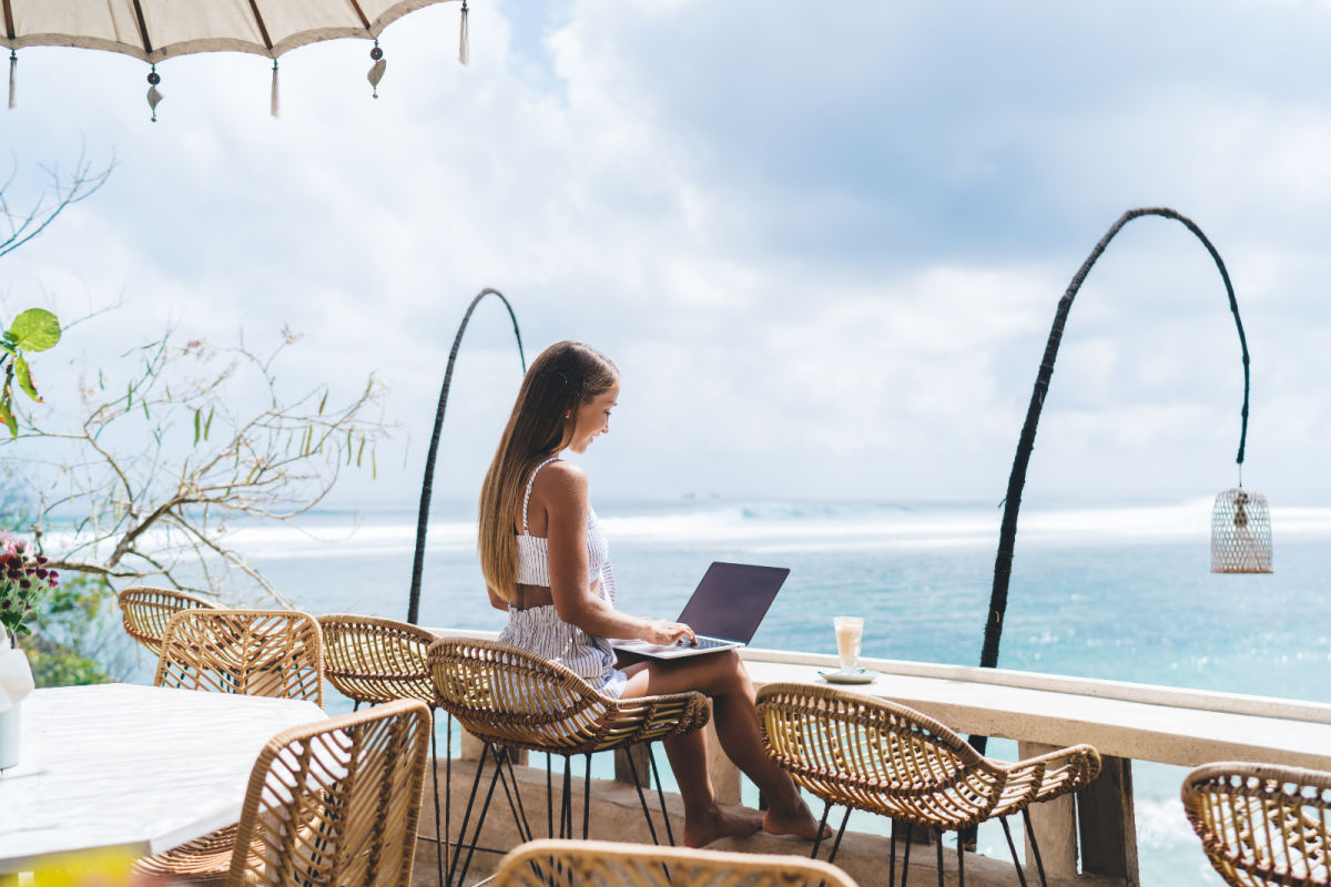 Digital nomad woman works at high table desk overlooking ocean in Nusa Penida.jpg