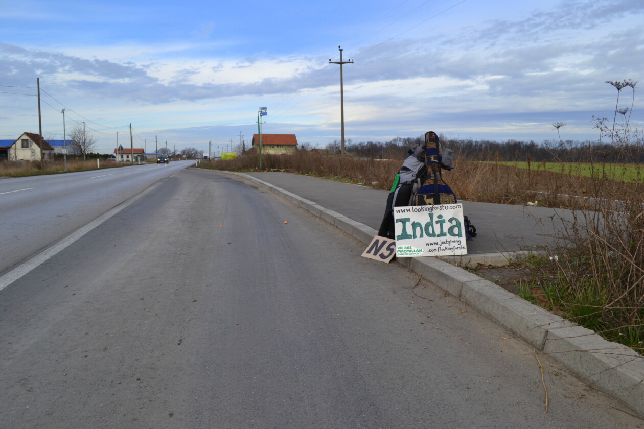 Hitchhiking signs and backpack by the side of a road in Serbia