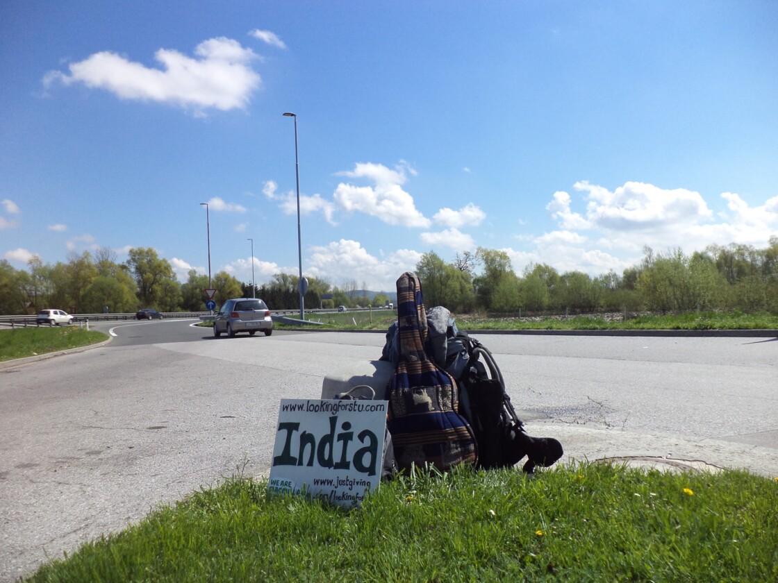 Hitchhiking sign backpack and guitar by the side of a road