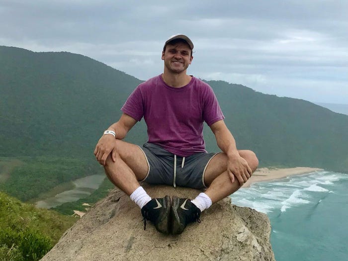 The author sitting on a rock overlooking a beach in Florianópolis, Brazil.