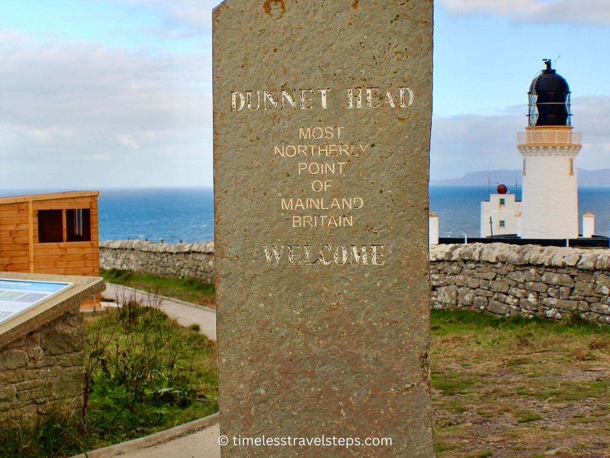 Dunnet Head pillar sign with the Dunnet Head Lighthouse in the backdrop © timelesstravelsteps.com