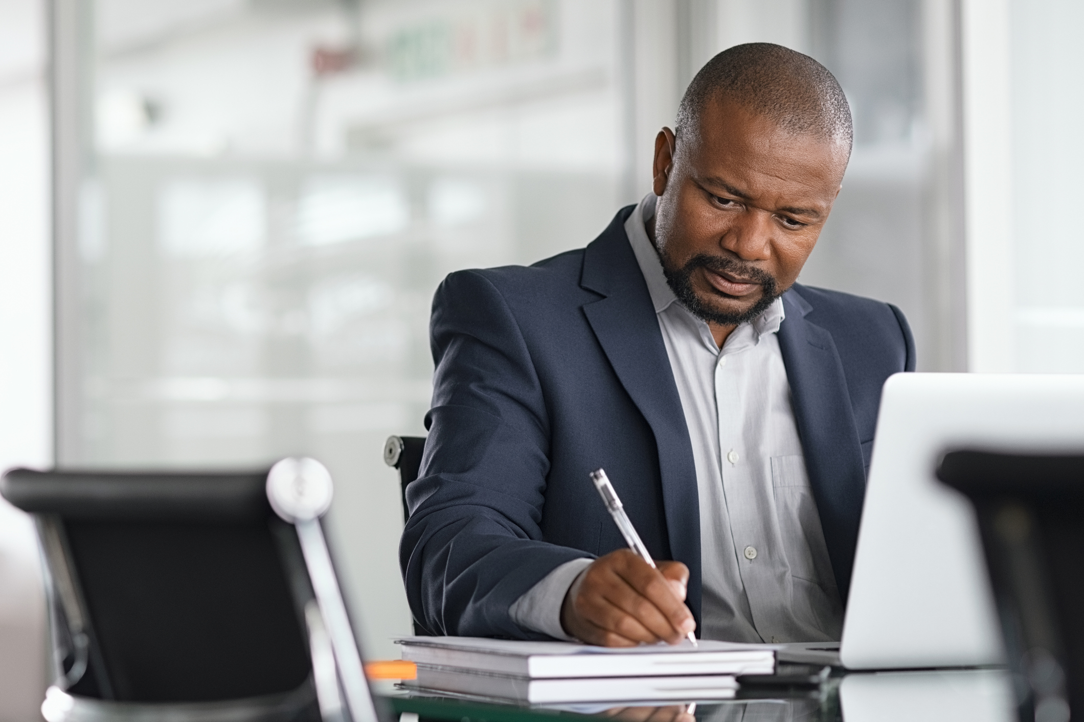 A person at a laptop holding a pen.