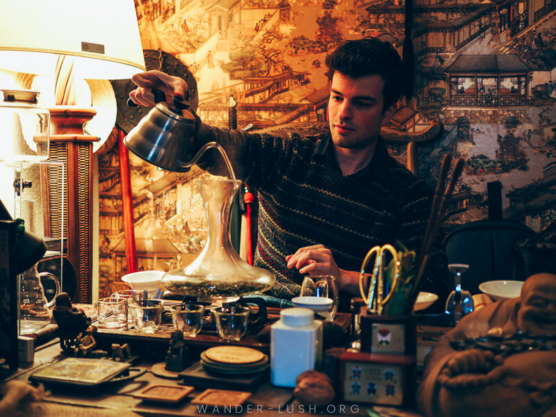 A man pours hot water into a glass decanter inside a tea shop in Tbilisi in winter.