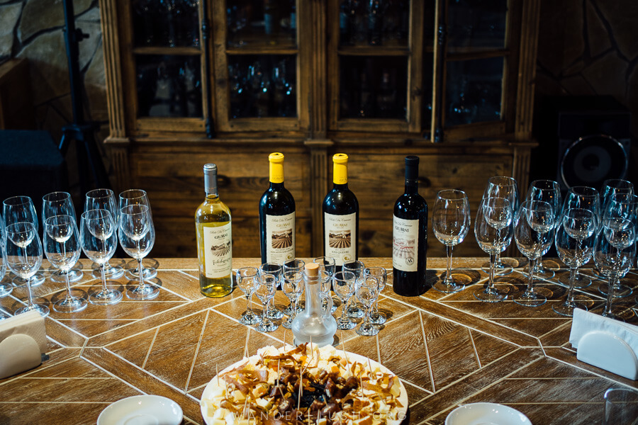 A table spread out with glasses, wine bottles and food.