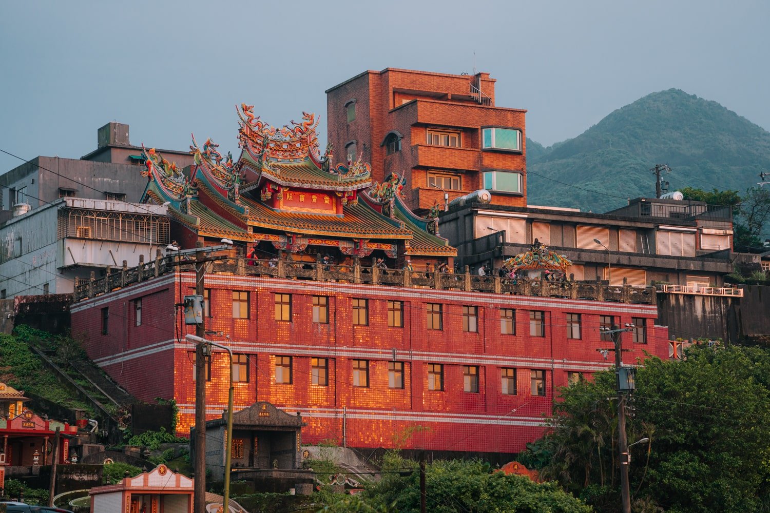 The Jiufen Tian Gong Temple illuminated by the sunset with photographers on the viewing deck.