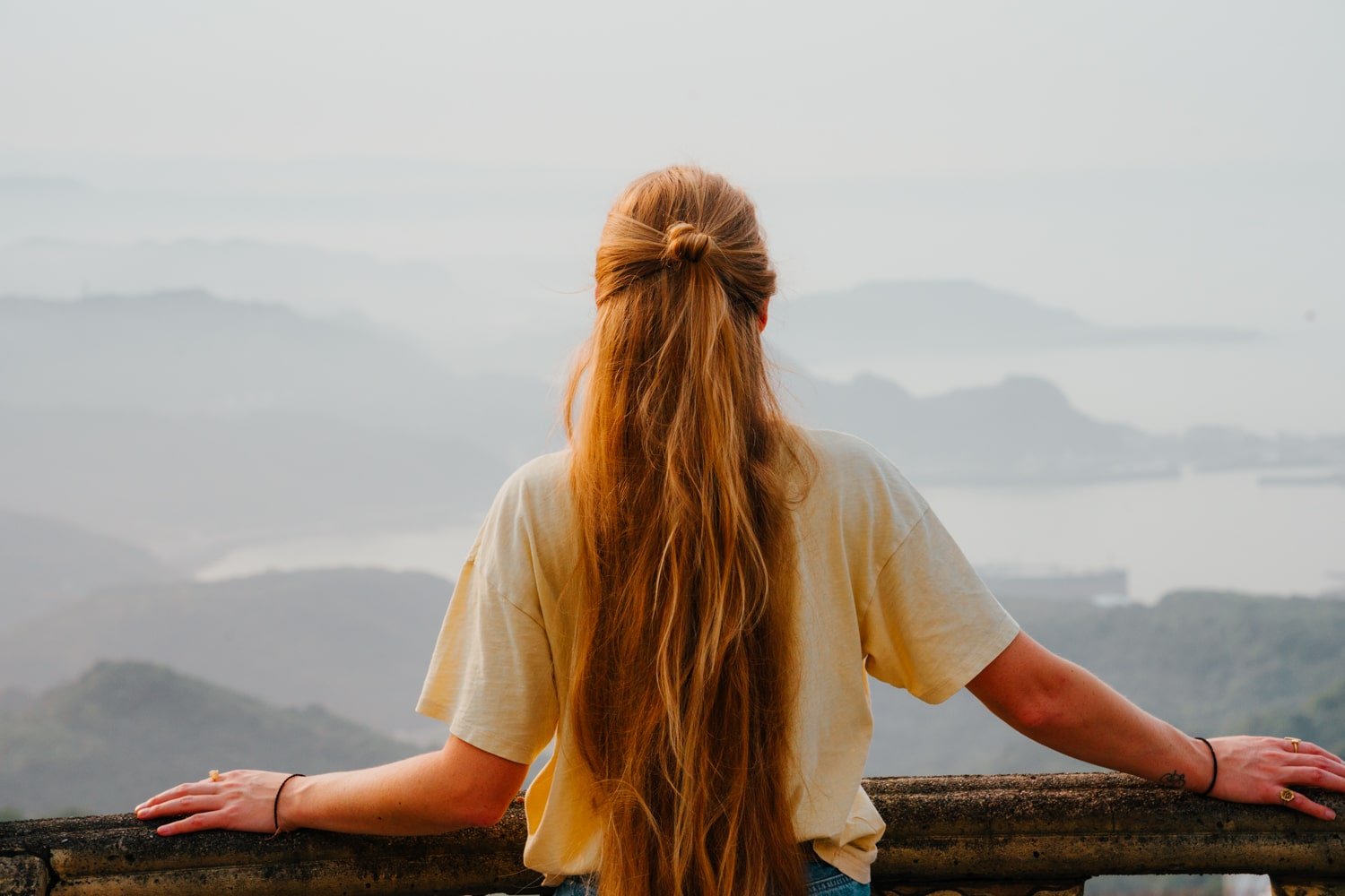 Woman with long blonde hair overlooks Keelung Bay from temple in Jiufen, Taiwan.