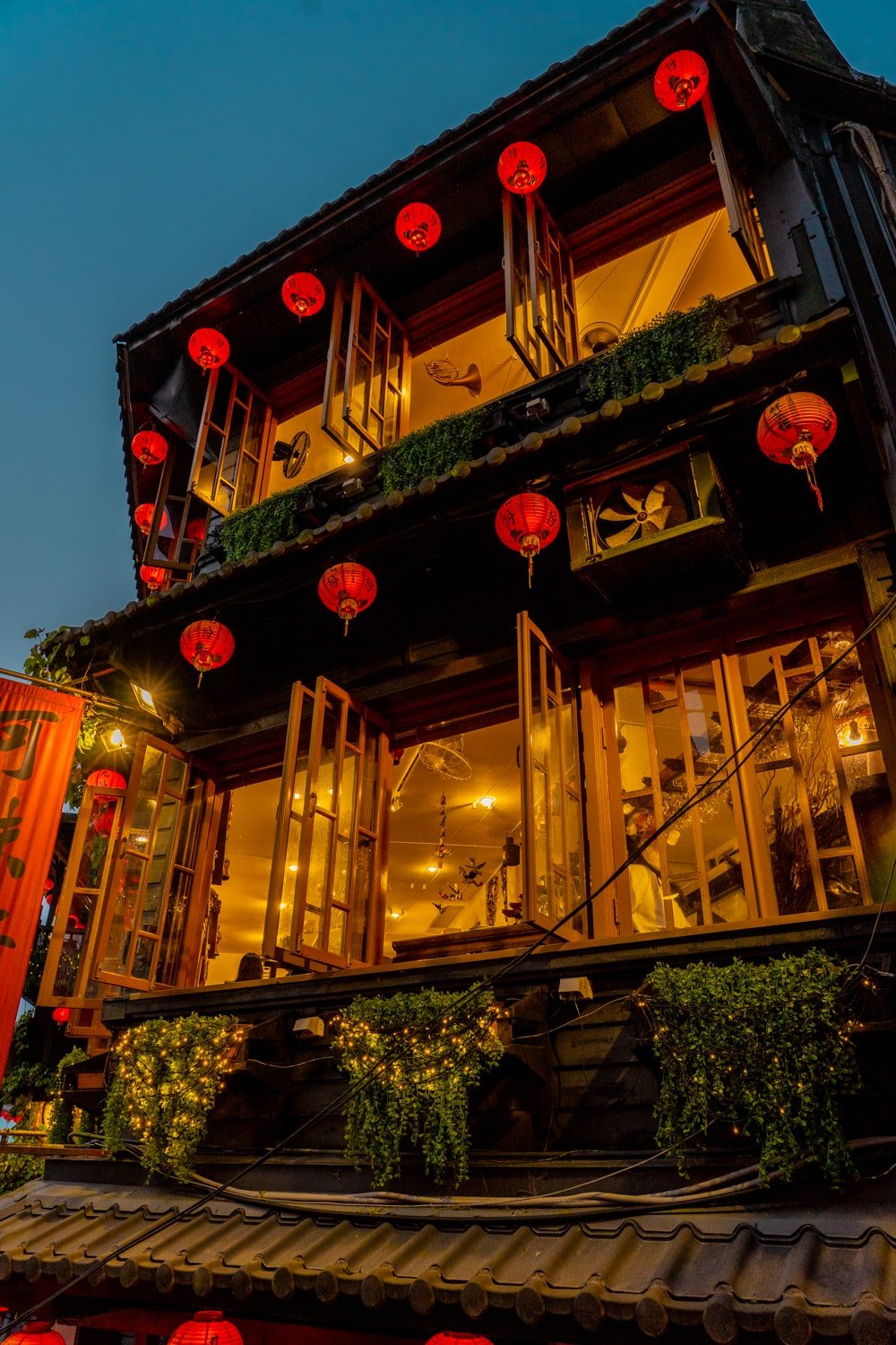 The Amei Teahouse in Jiufen, Taiwan lit up with lanterns and lights at dusk.