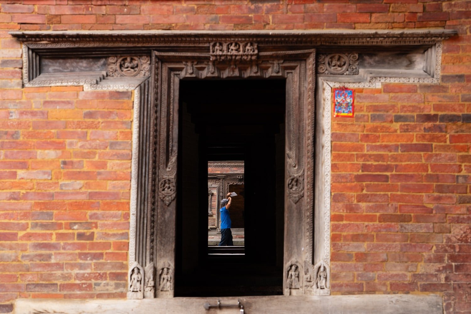 A man walks past the opening of a palace door in Patan's royal palace complex.