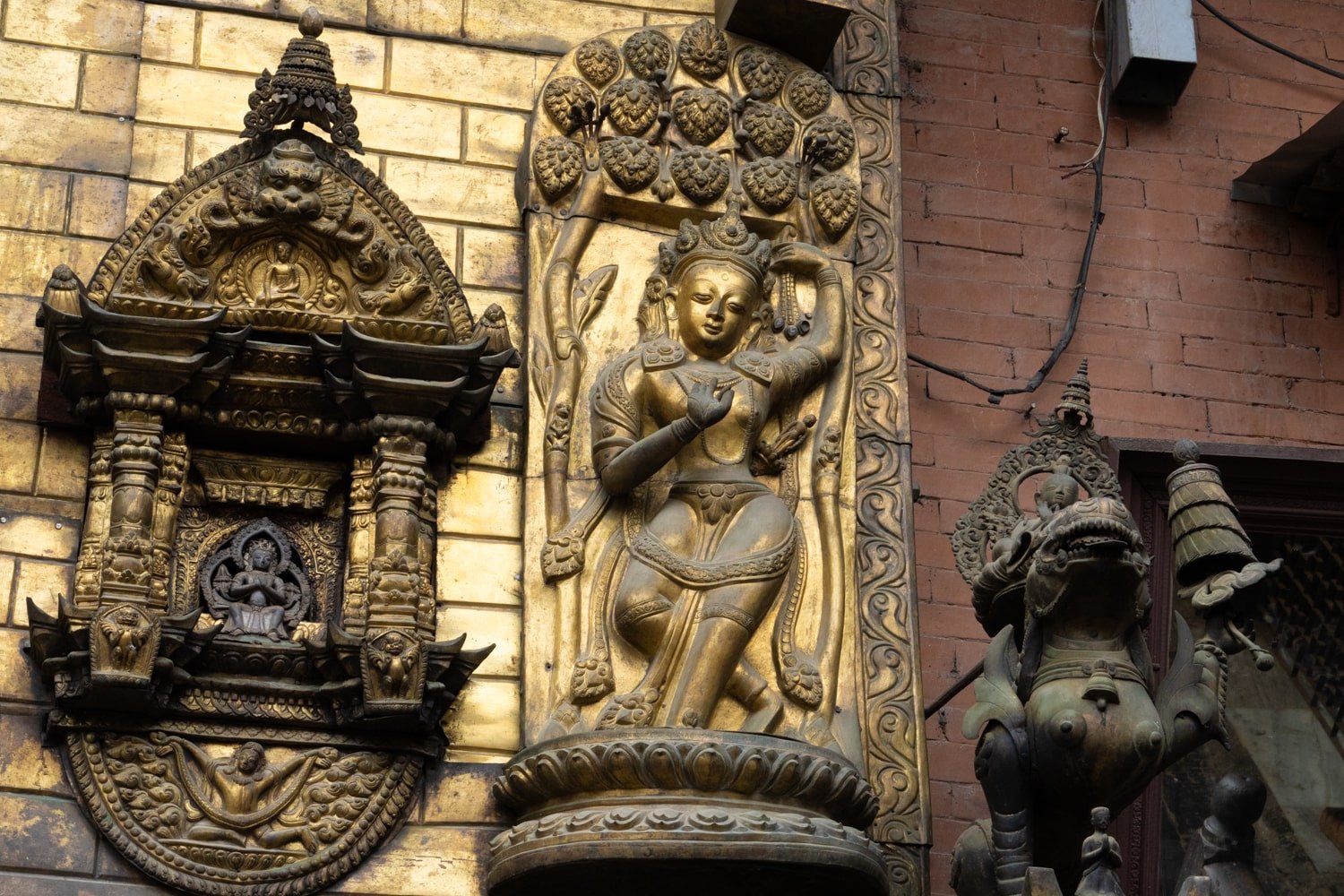 A golden statue and relic of Buddha's mother with baby Buddha coming out of her armpit.