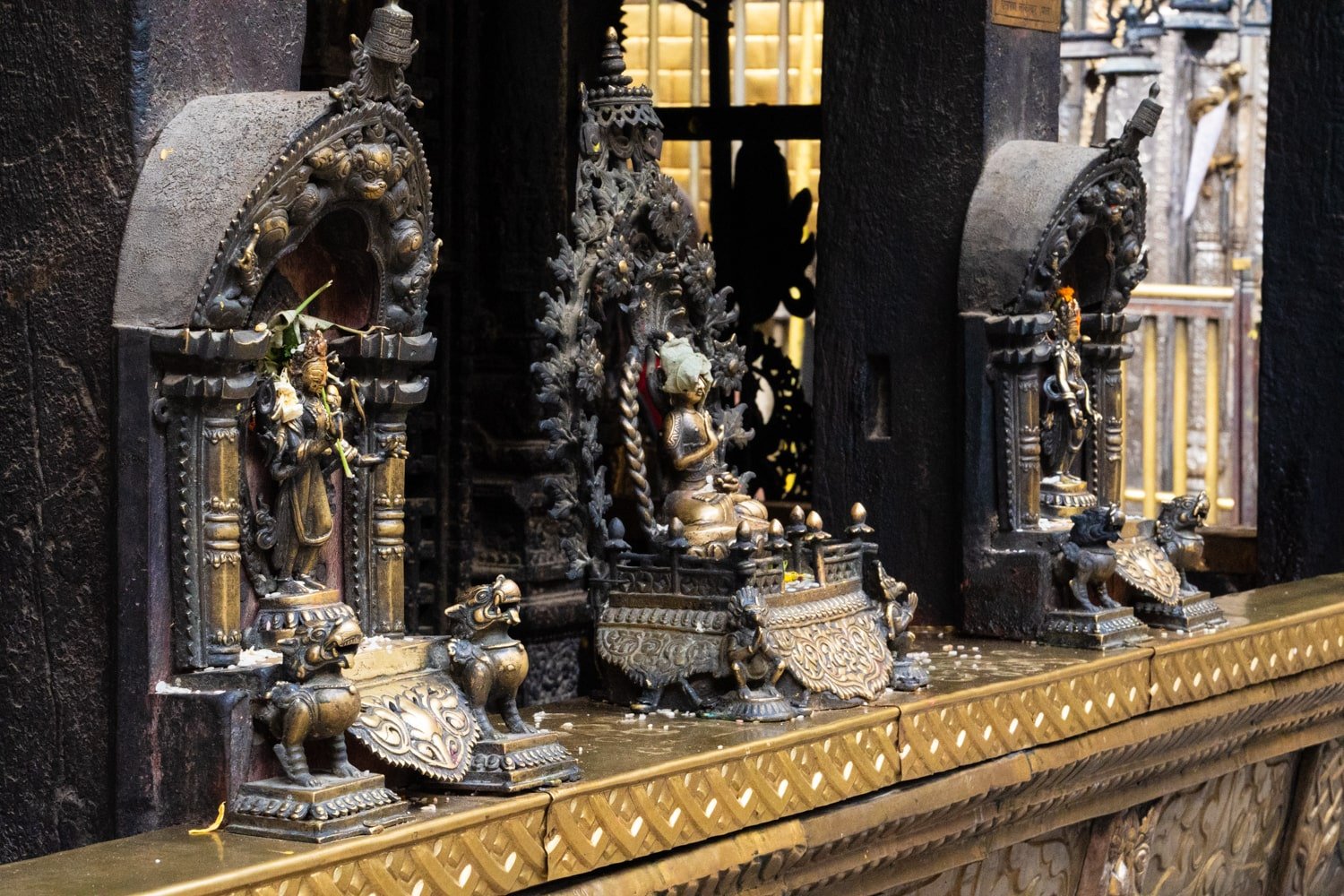 Three Buddhist and Hindu statues inside the Golden Temple of Patan Durbar Square.