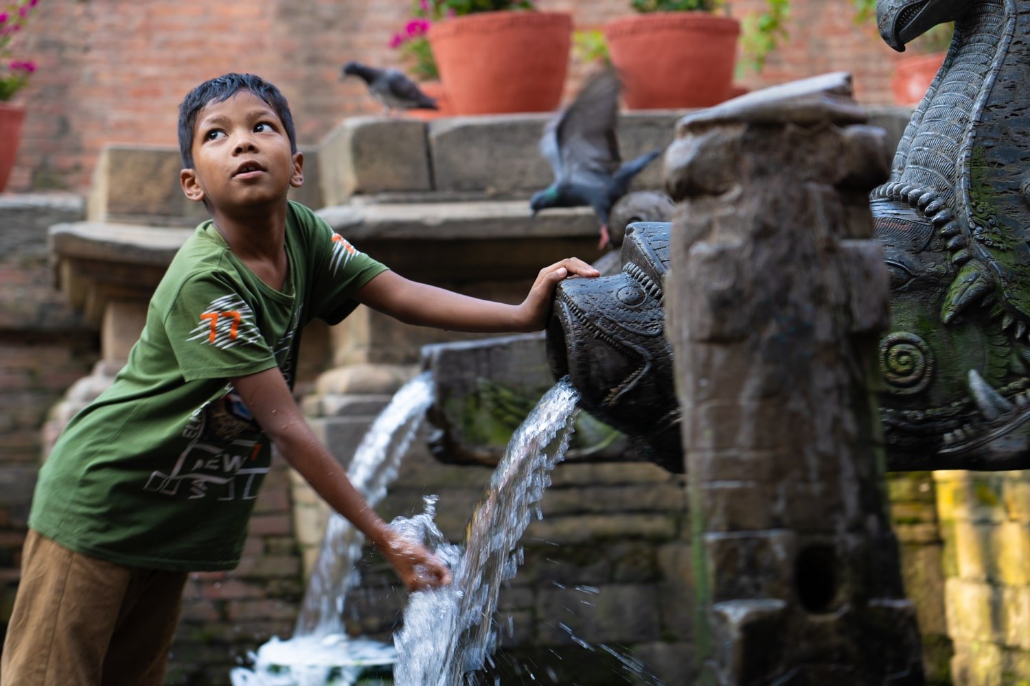 Newari Nepali boy washing hand at Manga Hiti fountain in Patan Durbar Square.