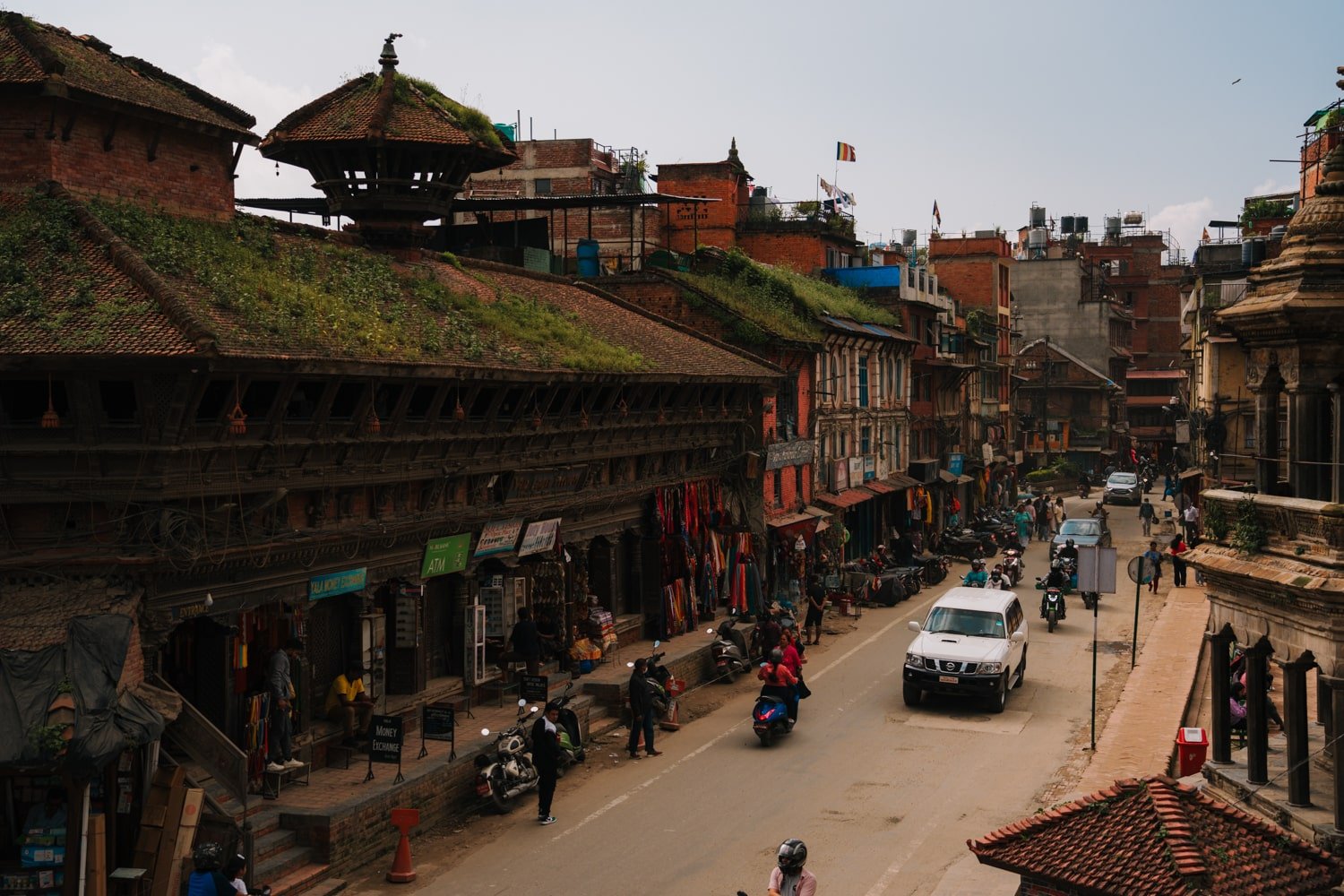 Cars and pedestrians on a street beside the entrance to Patan Durbar Square in Lalitpur.