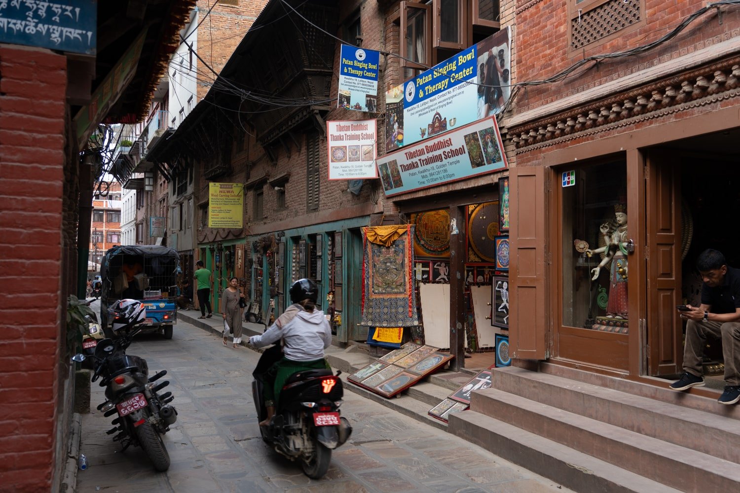 Motorcyclist and street shops around Patan Durbar Square, Kathmandu, Nepal.