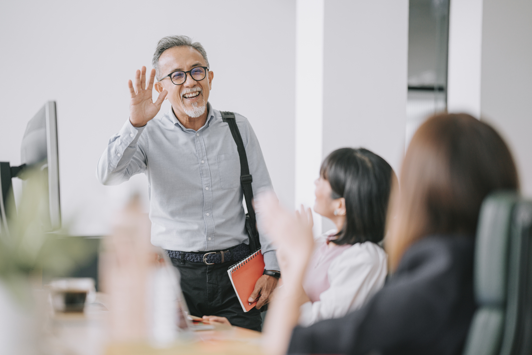 Person in office waving to coworkers.