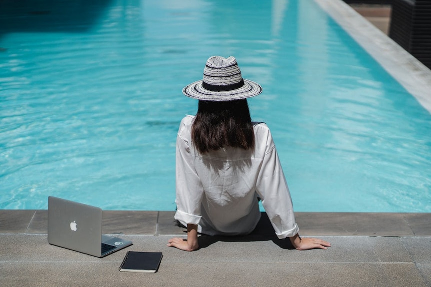 A faceless woman sitting at the edge of a blue pool