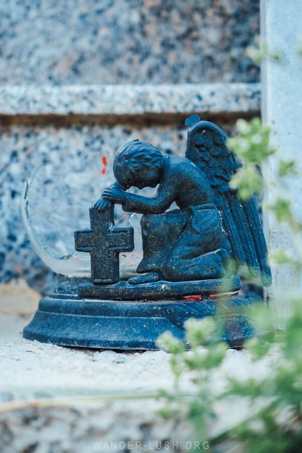 A statue of an angle and a cross in a graveyard in Albania.