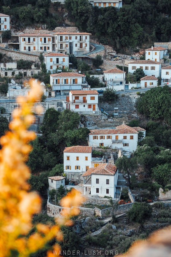 White houses in Dhermi fringed by golden foliage at sunset.