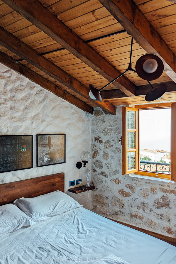 A cosy boutique hotel room in Albania with stone walls and a timber roof.