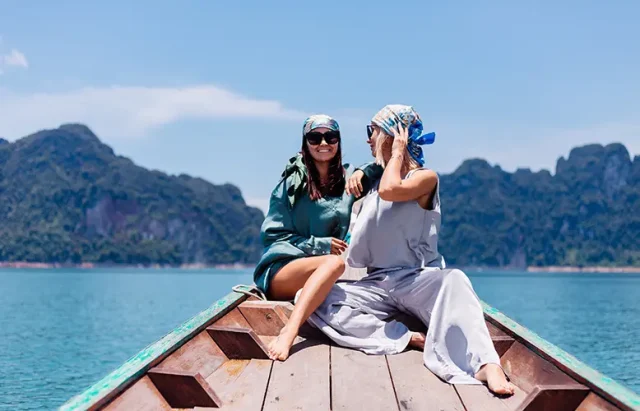 Two happy woman tourist at lake friends in silk suit and scarf and sunglasses on vacation