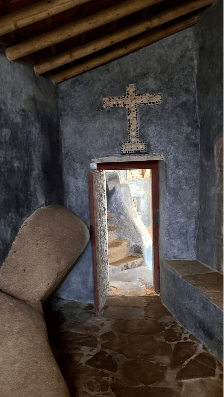 A blue room with a beam ceiling and a crucifix over the door in the Convent of the Capuchos.