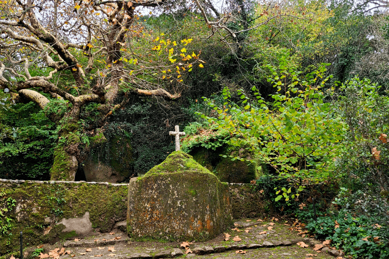 A crucifix on a stone wall covered in moss in the Courtyard of the crosses at Convent of the Capuchos