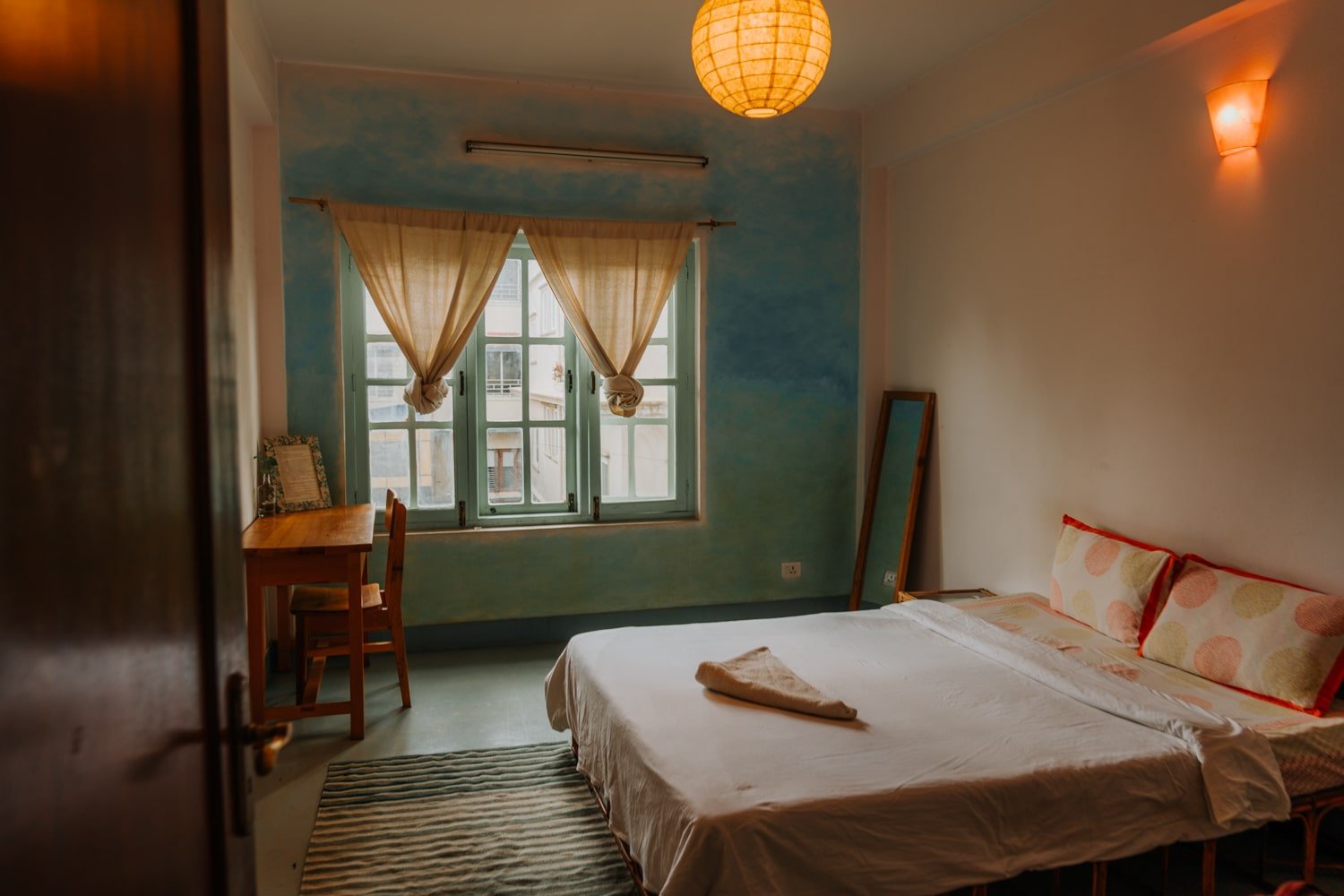 A private bedroom with queen bed, mirror, and desk with cozy lighting, at a hotel/homestay in Kathmandu.