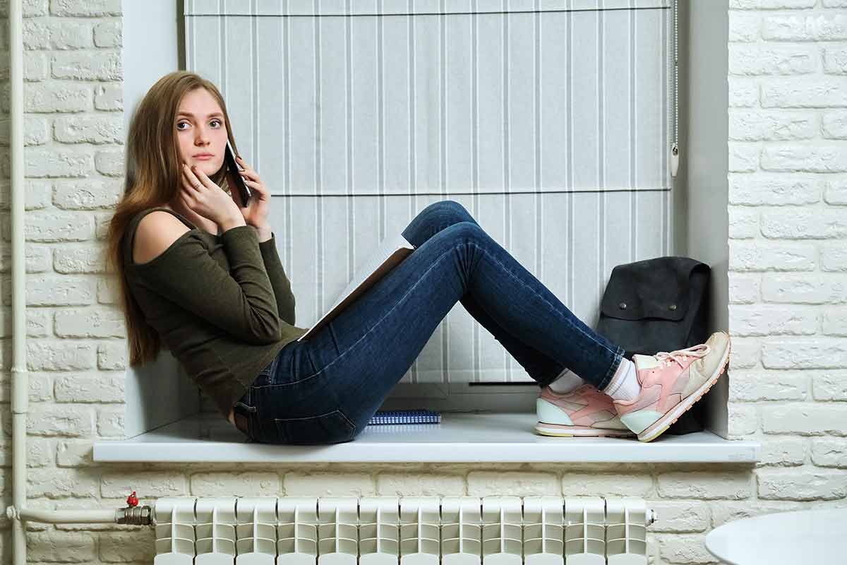 woman sitting in a doorway with a phone to her ear and a best minimalist backpack