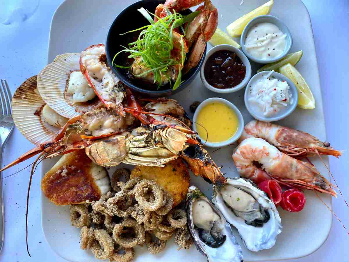 a selection of seafood such as oysters, lobsters, crab, squid and shellfish along with condiments on a platter