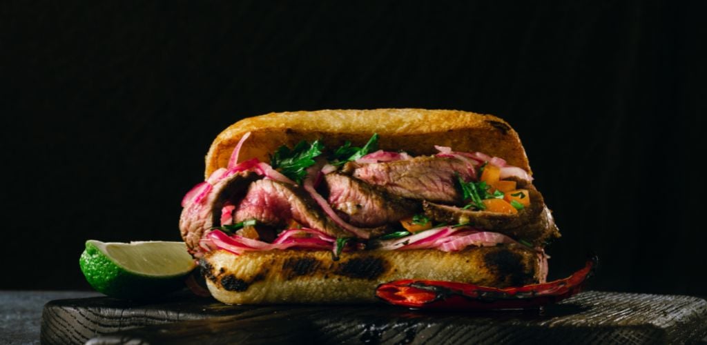 Grilled spicy steak sandwiches wooden cutting boards on dark background